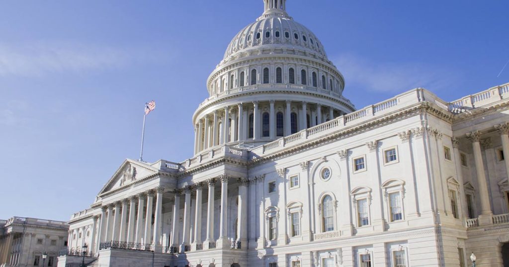 US Capitol building from a 3/4 view during the day with a blue sky.